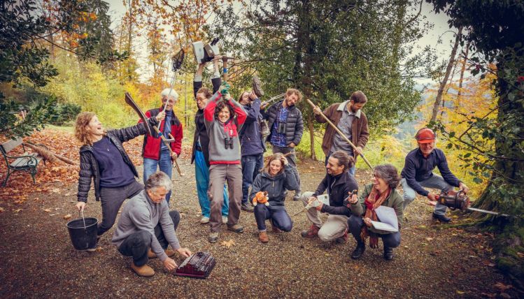 Teamfoto in Aktion. Mitarbeitende von Verein Grünwerk posieren in verschiedenen Stellungen mit passenden Werkzeugen.